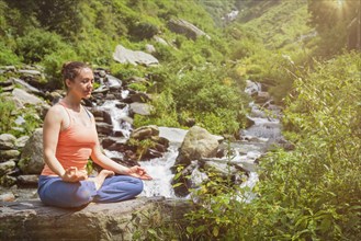 Woman in Hatha yoga asana Padmasana lotus pose outdoors