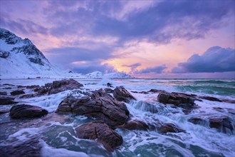 Waves of Norwegian sea on rocky coast in fjord on sunset with sun. Skagsanden beach, Lofoten