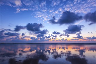 Sunset on Baga beach win clouds reflectin in wet sand. Goa, India, Asia