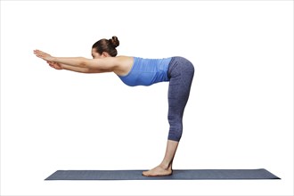 Woman doing yoga in standing forward bend pose transition to uttanasana on yoga mat isolated on