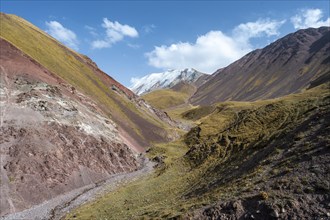 Valley with mountain stream between high mountains in autumn, mountain landscape with glaciated