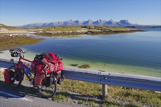 Packed touring bike, crystal clear water in a shallow bay, view of the mountain range Seven