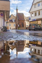 Street through the half-timbered town, historical building with reflection in puddle,