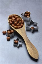 Wooden ladle with hazelnuts, cookie cutters, baking ingredient