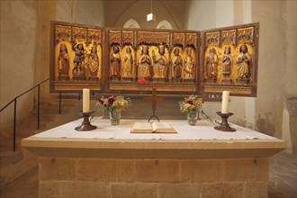 Interior view and folding altar with candles, bible and bouquet of flowers of the Romanesque