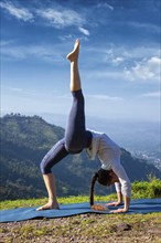 Yoga outdooors, woman doing yoga asana eka pada urdva dhanurasana Upward Bow Pose back bend