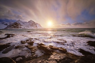 Beach of Norwegian sea on rocky coast in fjord on sunset in winter. Vareid beach, Lofoten islands,