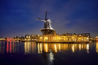 Night view of Harlem landmark windmill De Adriaan on Spaarne river in twilight illuminated. Harlem,