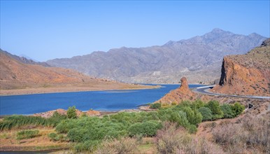 Blue Toktogul reservoir between dry mountain landscape with red mountains, Jalalabad region,