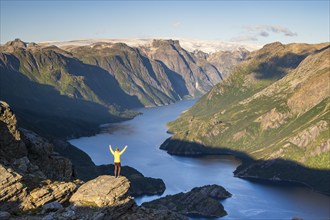 Hiker looking from Seiskallåfjellet into the Nordfjorden, Svartisen Glacier in the background,