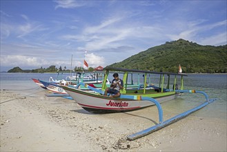 Indonesian tourist guide playing ukulele on outrigger boat on the islet Gili Nanggu, Gili Islands,