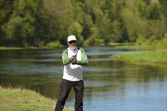 Fisherman trying to do a perfect cast, throwing lure. Spining fishing, angling, catching fish.