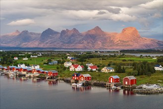 Boathouses of the village Herøy, behind the mountain range Seven Sisters, light mood, island Herøy,