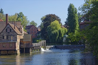 A historic mill building and industrial museum next to a waterfall on a sunny day, Lauf an der