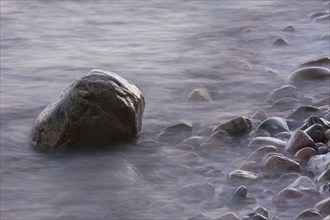 Rocks and pebbles on beach in the surf at low tide, Germany, Europe