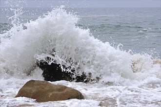 Wave crashing into boulder in the surf at the Côte Sauvage, Wild Coast, Quiberon, Brittany, France,