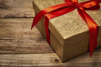 Gift present birthday Christmas concept, gift box with red ribbon on wooden background close up