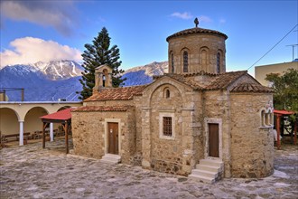 Byzantine church, dome, bell centre, tree, snow-capped mountains, cloudy blue sky, Myriokephala,