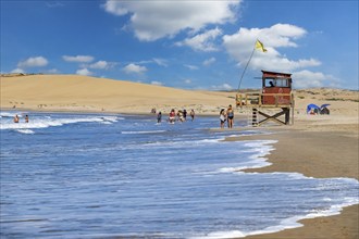 Lifeguard tower and tourists walking on the beach at Barra de Valizas, seaside resort, balneario