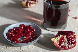 Glass of pomegranate juice on a white concrete background. Hard light, contrast. Side view, close