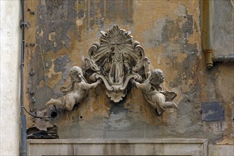 Putti holding an ecclesiastical symbol above an entrance door to a crypt, historic centre, Piazza