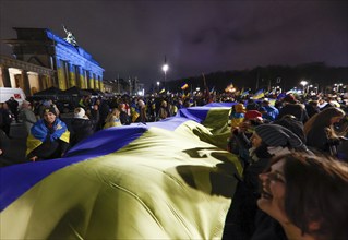 People demonstrate with a huge Ukrainian flag at the Brandenburg Gate on the anniversary of the