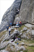 Children rock climbing on the granite tor of Haytor, Dartmoor national park, Devon, England, UK