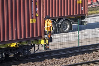 Shunter, railway employee steering the freight train with containers from the running board of the