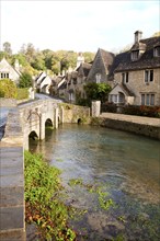 Bybrook River running past stone cottages in Castle Combe, Wiltshire, England, UK claimed to be