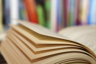 Close-up of an open book, behind it a blurred bookshelf