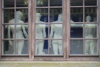 From behind sculptures, male figures, cast collection in the window from the outside, plaster