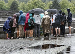 Visitors to the Memorial to the Murdered Jews of Europe protect themselves from heavy rainfall with