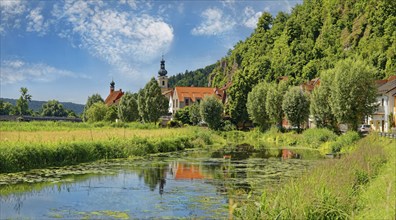 Church of St Michael with reflection in the tributary of the river Naab, surrounded by dense