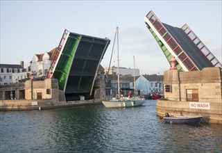 Town bridge raised to allow a yacht to pass into the marina in Weymouth harbour, Dorset, England,