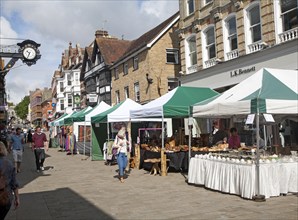 People shopping in busy pedestrianised street with market stalls in Winchester, Hampshire, England,