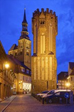 The Owl Tower at Hühnerdorfer Tor, built in brick Gothic style and illuminated at night, in the old