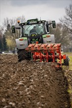 Tractor with a plough preparing the soil of a field for planting, Agriculture, Spring