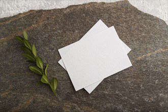 White paper business card, mockup with natural stone and boxwood branch on gray concrete background