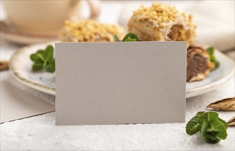 Gray paper business card and set of eclair on gray concrete background. side view, close up,