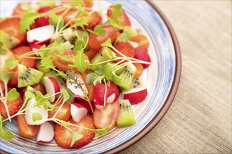 Vegetarian fruits and vegetables salad of strawberry, kiwi, tomatoes, microgreen sprouts on black