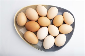 Pile of colored chicken eggs on plate isolated on white background. top view, flat lay, close up