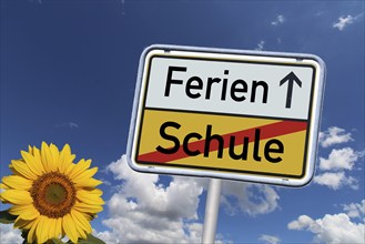 Symbolic image: German town exit sign with the words Schule/Ferien against a blue sky