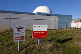 Signs boundary and no drone zone with white dome of Sizewell B power station, Suffolk, England, UK