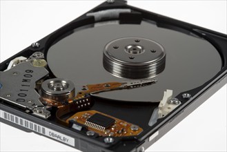 Computer hard drive, opened, read/write head on the storage disc. Symbol image