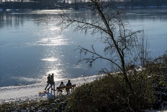 Winter in the Ruhr area, Lake Baldeney, snow-covered, partly frozen lake, walkers on the lakeside