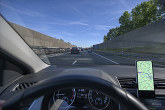 Driving on the A73 motorway with navigation by mobile phone, noise barriers on the left and right,