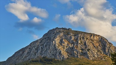 The sun shines on a rocky mountain under a cloudy blue sky, Archaic Castle, Akrokorinthos, Corinth,