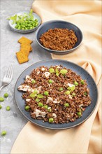 Quinoa porridge with green pea and chicken on ceramic plate on a gray concrete background and