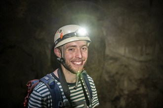 Young man with helmet and headlamp in a stalactite cave, Terciopelo Cave, Barra Honda National