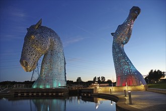 The Kelpies, two monumental horse sculptures, glow in bright colours at night, Forth and Clyde